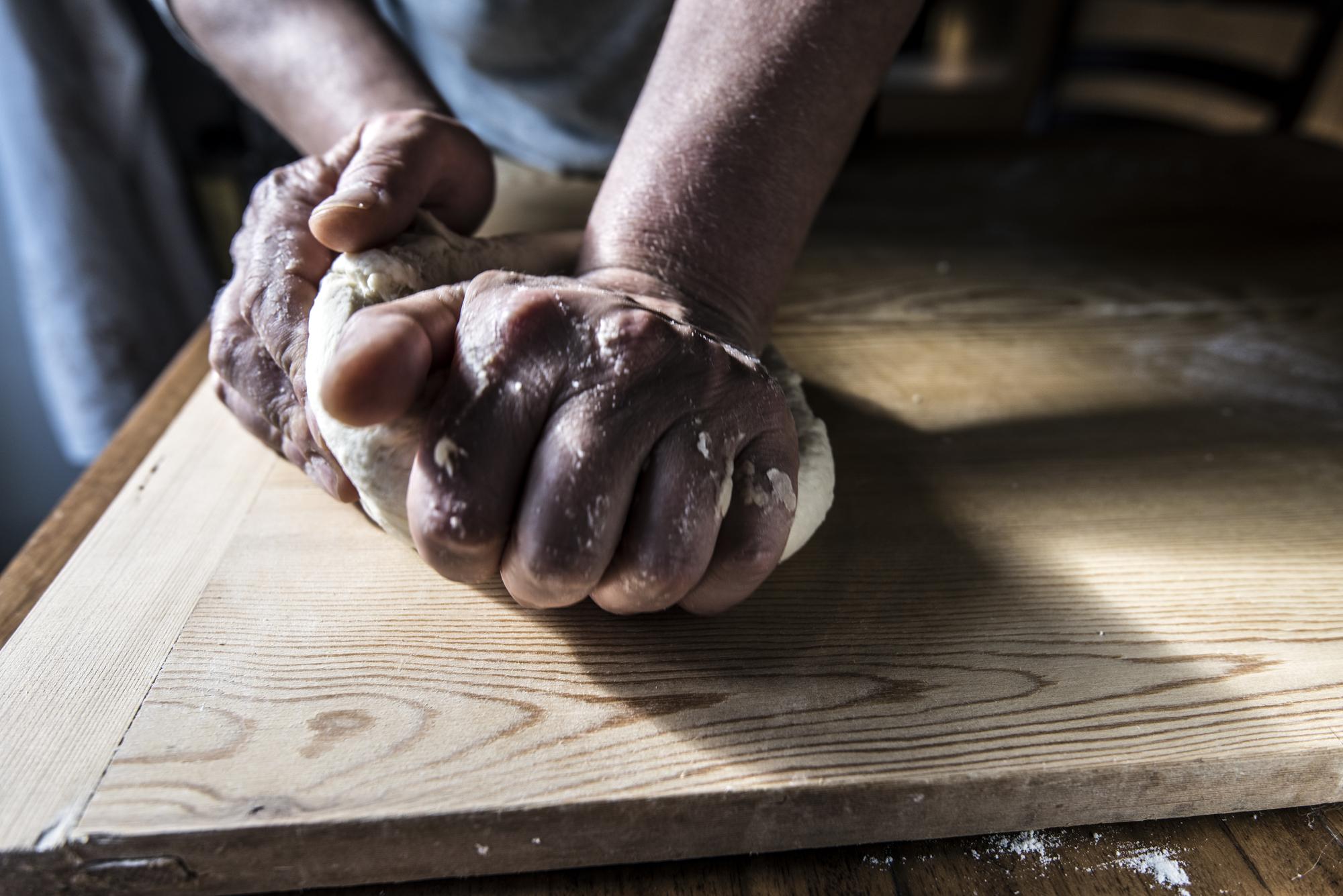 Close-up of artisan hands kneading dough on wooden table