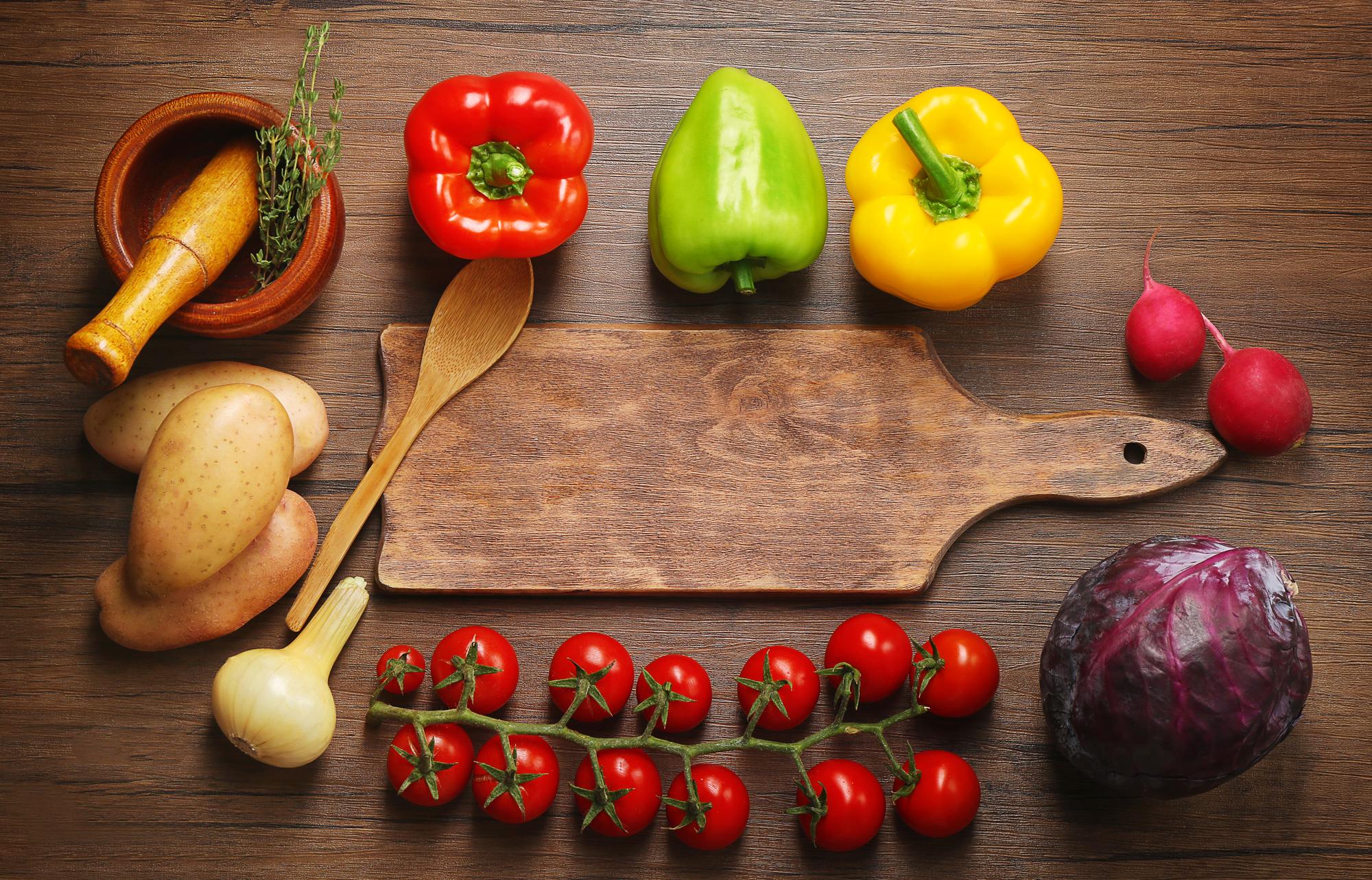 Wooden cutting board with colorful vegetables and tools